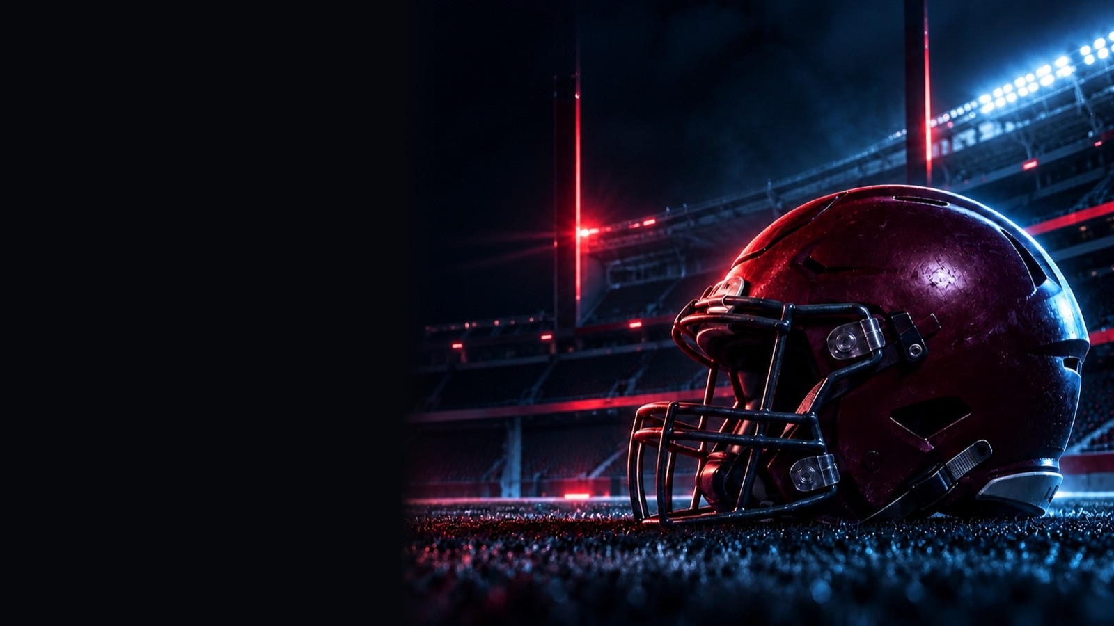 Maroon football helmet resting on turf inside a dark stadium